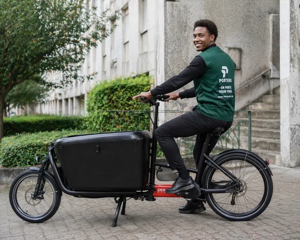 Intervenant PORTERS sur un vélo cargo devant un immeuble
